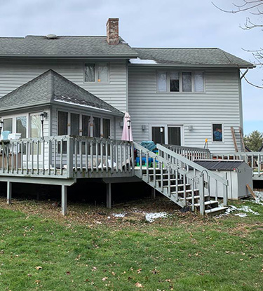 A before shot of a large home with a wood deck before its renovation