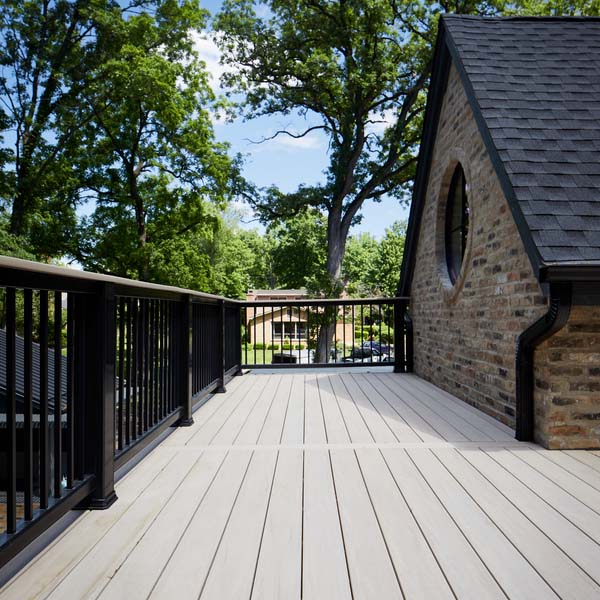 A deck made with French White Oak decking on a brick-clad home