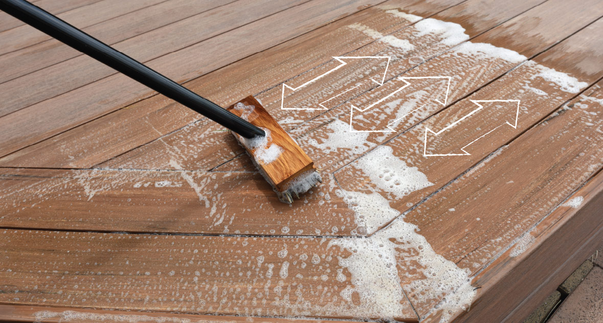 A soapy deck brush scrubs with the grain to clean the deck's surface.