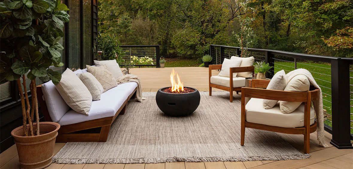 Neutral deck furnishings and a cozy fireplace look warm and inviting.