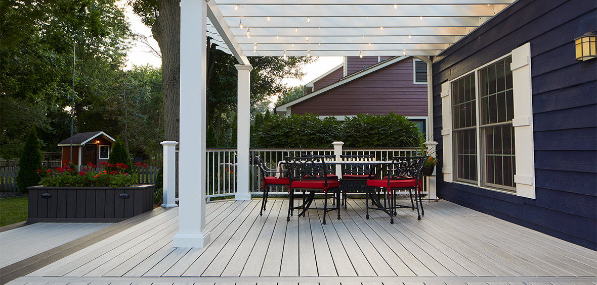Deck and seating covered with white pergola and string lights.