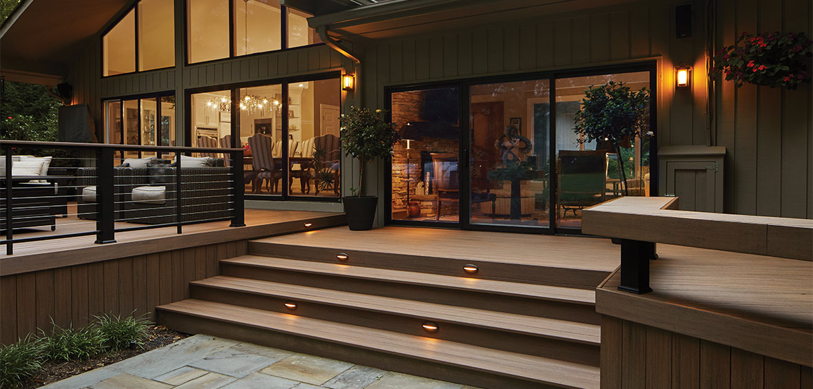 Wide deck steps lead to multiple deck levels and a large glass door.