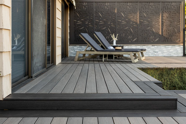 Two lounge chairs on a gray deck with dark grey-brown deck boards that frame the edges