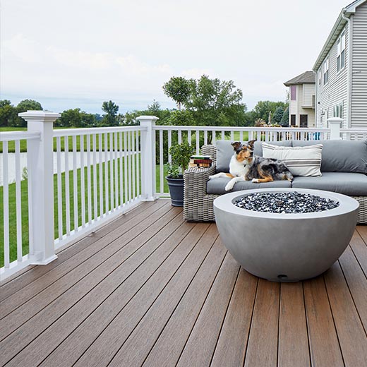 A dog patiently sits on an outdoor couch on a cloudy day