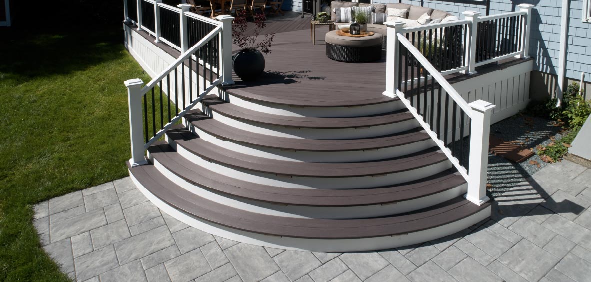 Curved steps open at the corner of a deck to provide access to the patio below.
