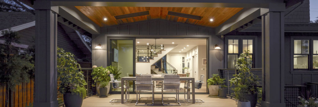 A back deck at dusk features an overhang protecting the deck and furniture below it.