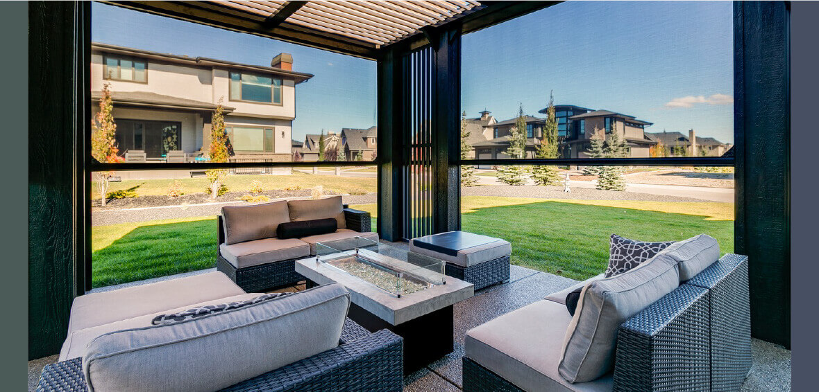 A backyard pergola with couches and a tabletop fire pit showcase motorized screens half down on each side.