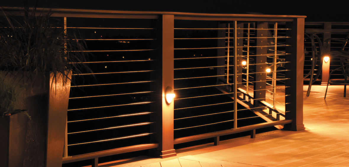 A photo at night shows how built-in railing lights illuminate a decking floor for ambiance and safety.