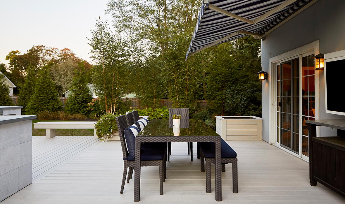 A dining arrangement on a deck is protected from the sun by an adjustable awning.