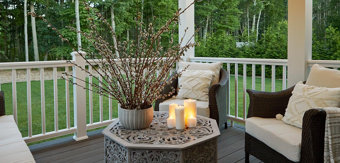 Deck seating area with candles atop a small, ornate table.