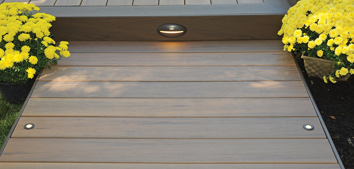 A deck walkway with lights installed in floorboards and risers for safe steps.