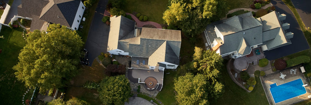 An overhead image of three homes in a neighborhood, showcasing decks, pools, playgrounds, and other home features.