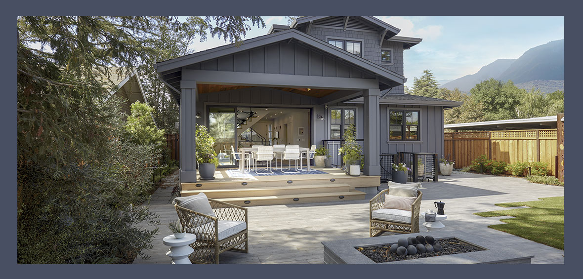 A back patio with a firepit and chairs connects to a covered back deck with a dining set.