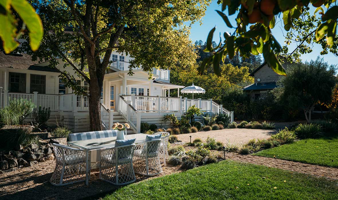 Outdoor patio furniture is shielded from the sun by beautiful green shade trees.