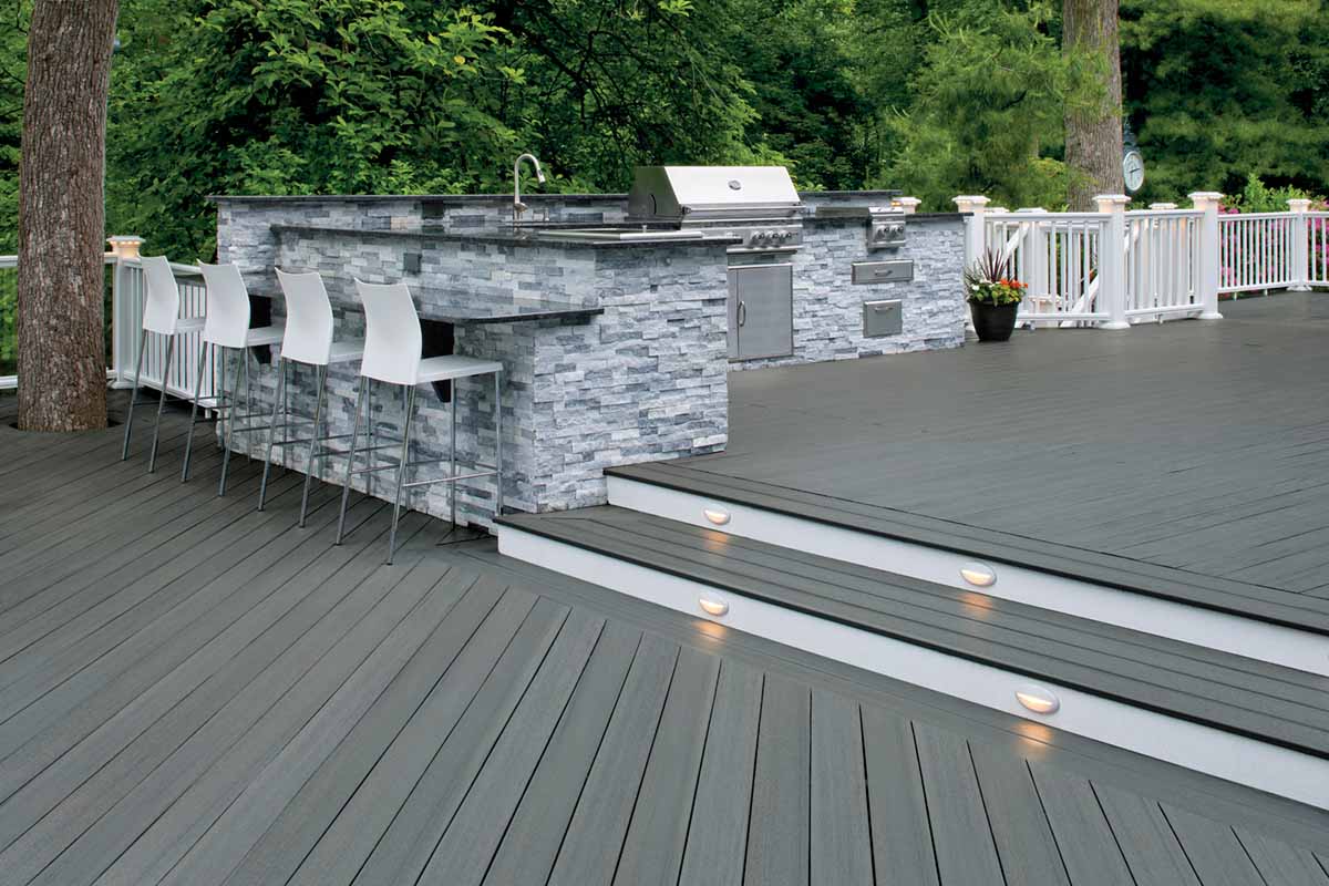 Multi-level medium gray deck with a bar and grilling area separated by a small set of stairs