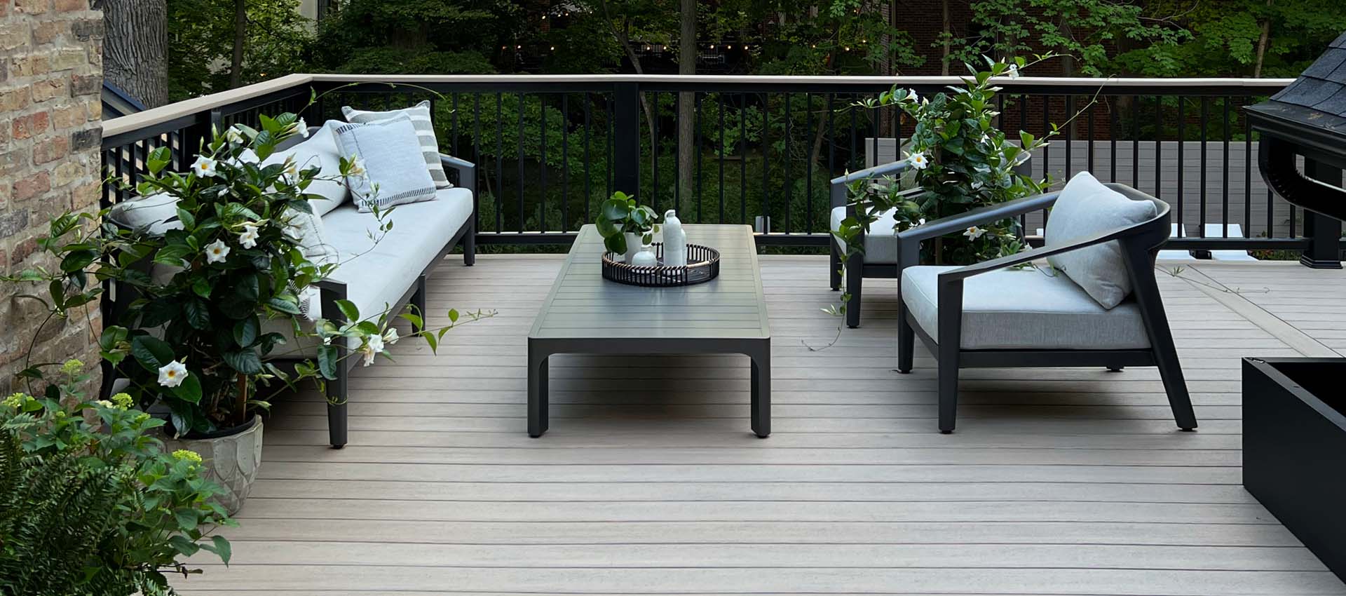 Light tan deck boards with mid century modern furniture and beautiful flowering plants with vines