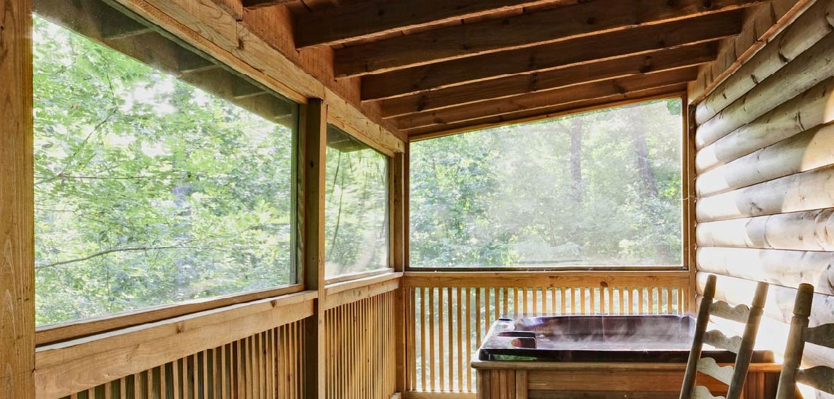 A balcony with a hot tub includes a few seats with a roof providing overhead protection.