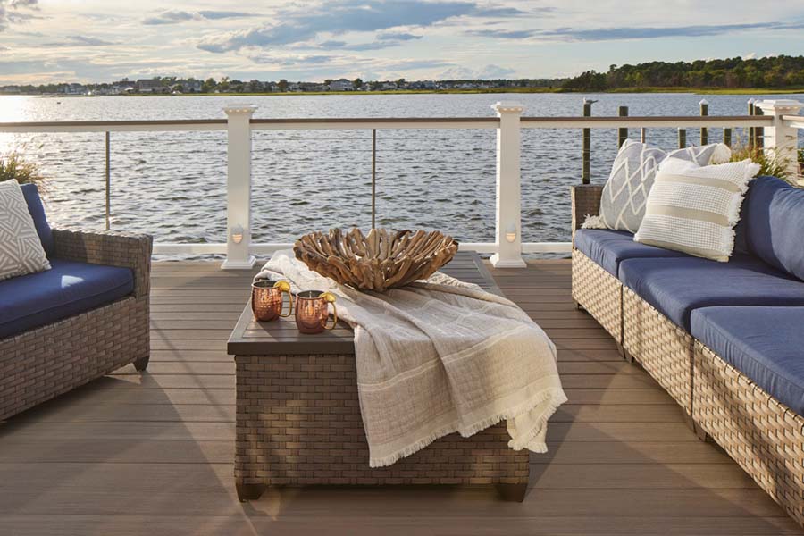 Deck looks out on the water with two blue sofas and a coffee table with a decorative bowl and throw cloth