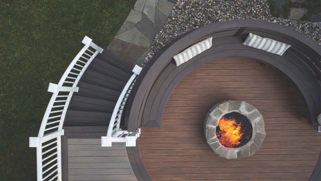 Aerial photograph of a circular mahogany deck with a fire pit and winding stairs that hug the deck