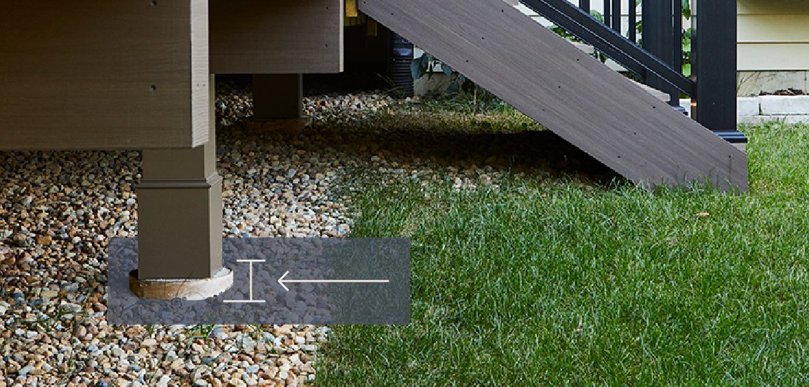 A close up of deck posts shows where the post is secured by a concrete footing in the ground. 