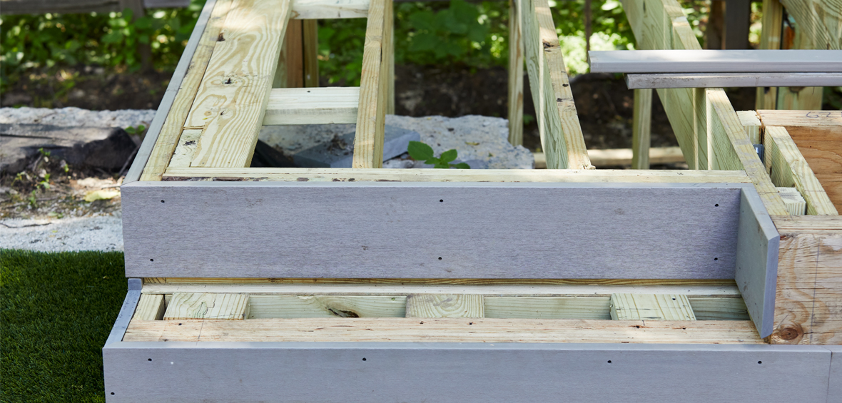 A close up of an in-progress deck build shows the substructure including joists, blocking, and rim boards.