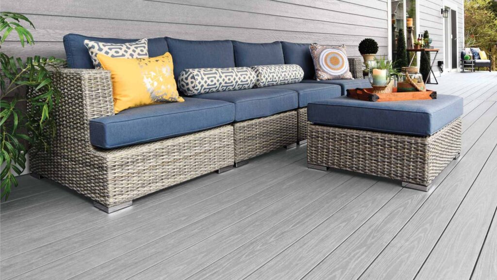 House with light gray siding and matching decking with a wicker outdoor couch