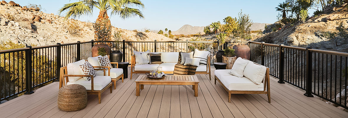 A deck overlooks desert hills and palm trees with a white-cushioned outdoor living furniture set centered to enjoy the view.