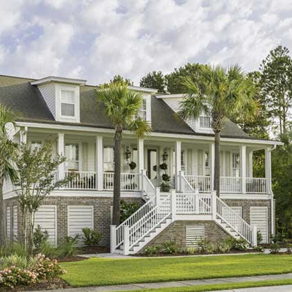 Palm trees line the grand staircase leading up to a traditional style white home