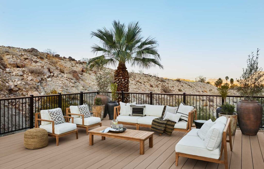 Palm trees and rocky hills surround a secluded deck in the desert