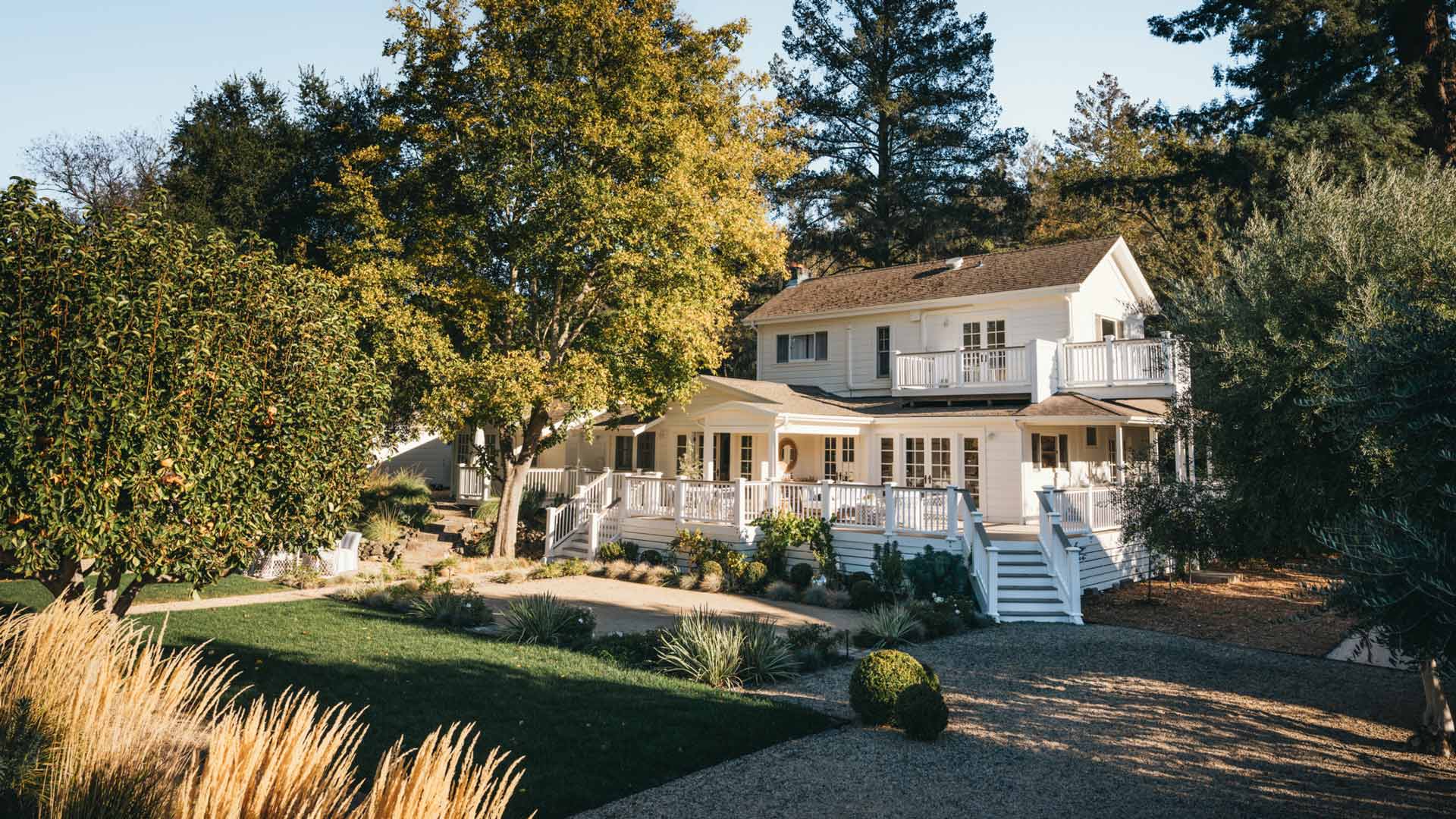 Far-away shot of a large, white home surrounded by trees