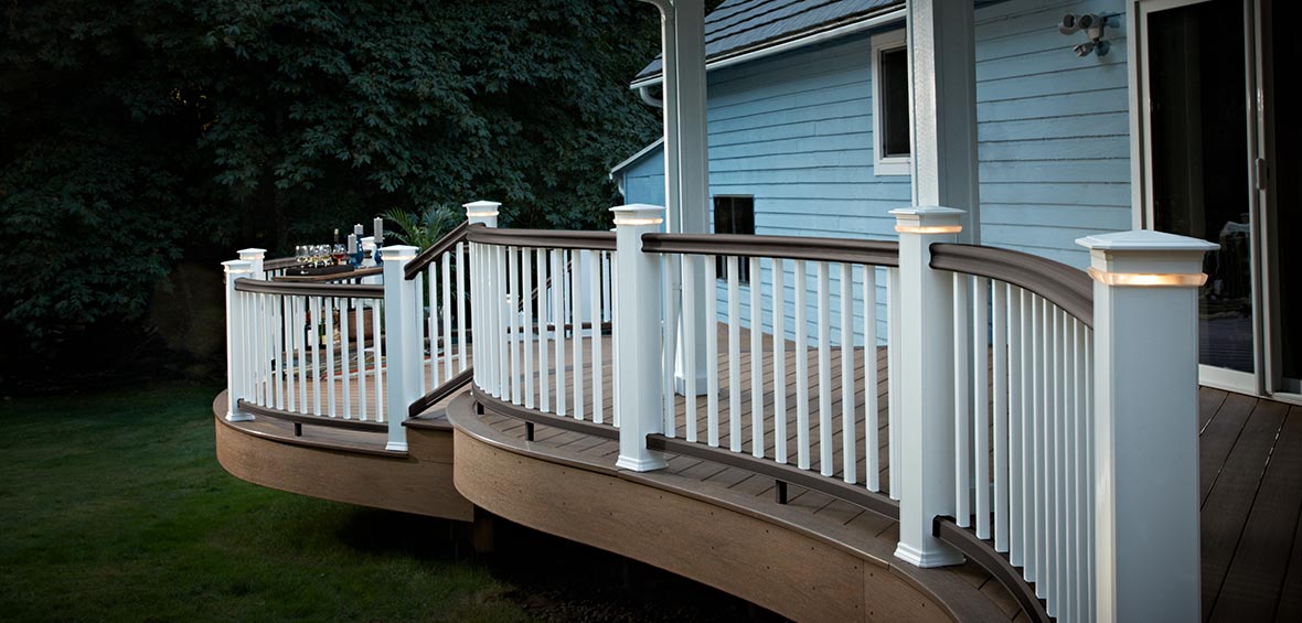 A brown deck edge is curved in the shape of waves with a matching white railing.