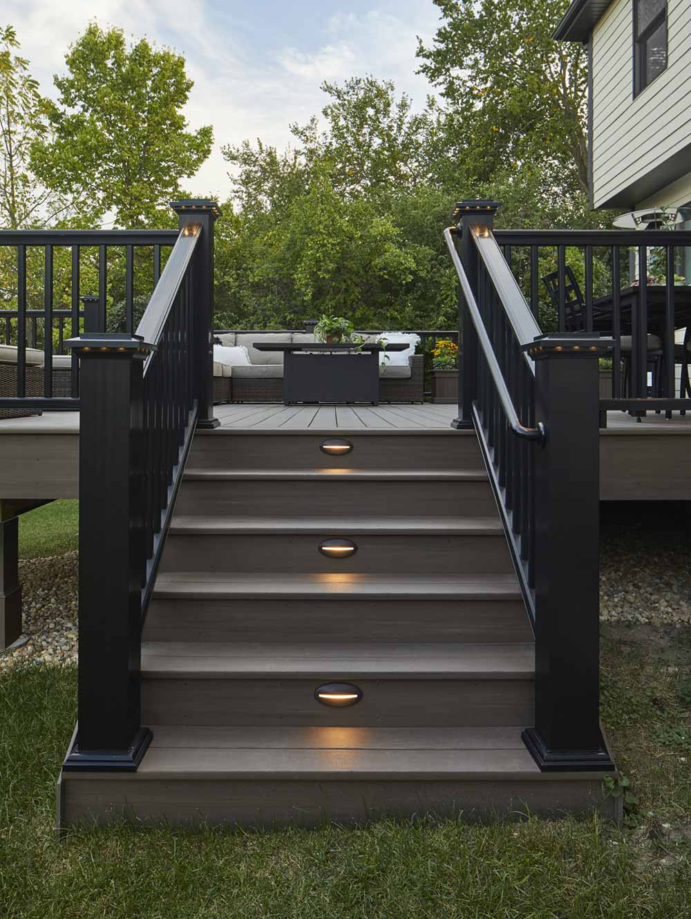 Deck with stairs, built-in riser lights, and a sleek black railing