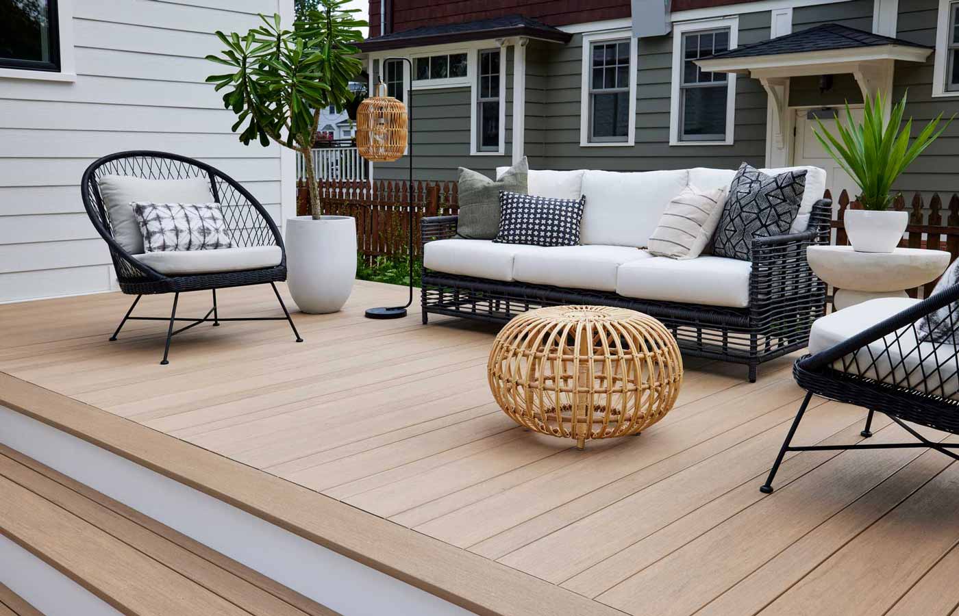 Woven outdoor furniture on a tan deck with a wide staircase leading up to it