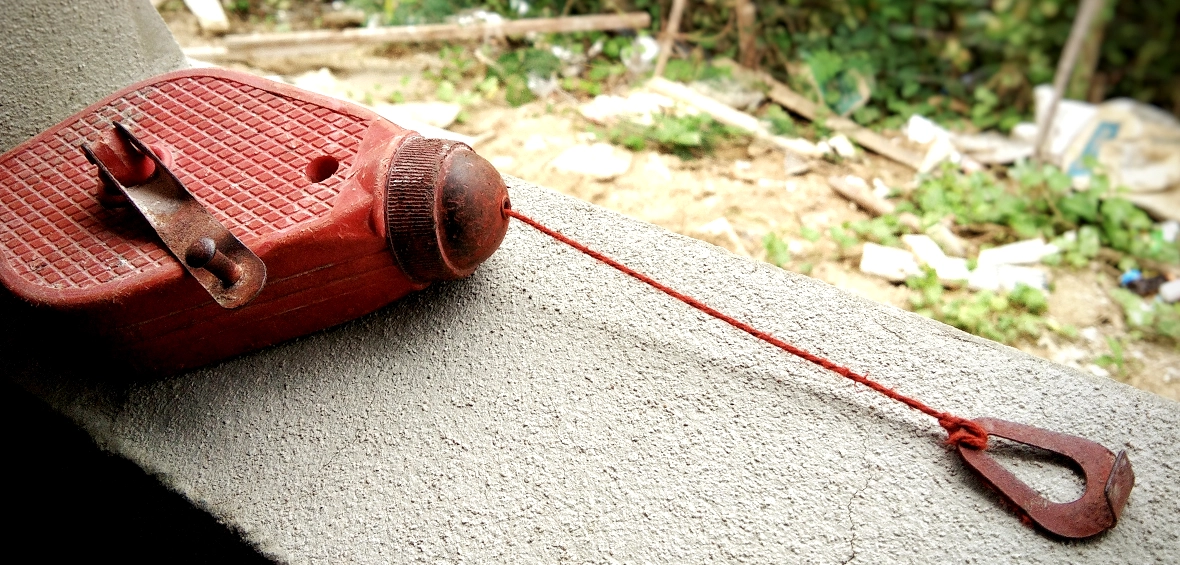 A red, plastic chalk line shows the chalk-coated line pulled a couple inches out of its reservoir. 