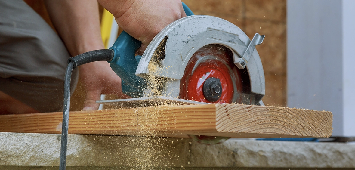 A stand-free circular saw is shown cutting a piece of lumber with sawdust kicking up. 