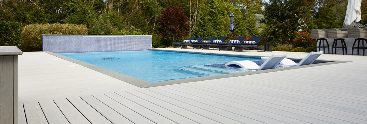 An in-ground pool with a deck and built-in fountain.