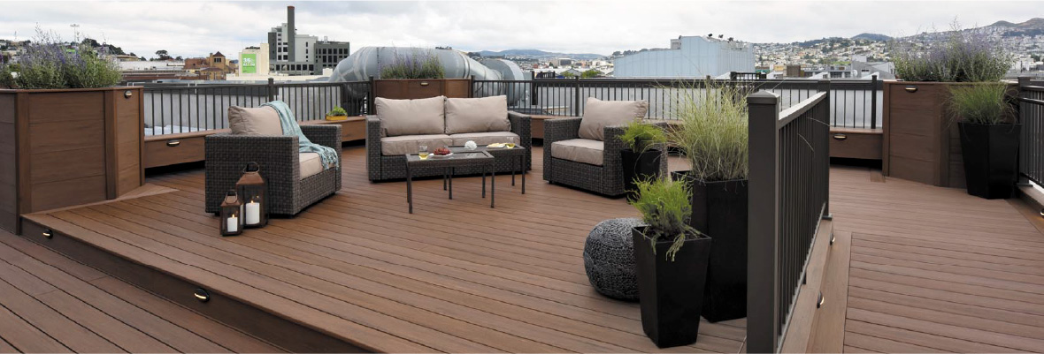 A multi-level composite deck features railing and planter boxes surrounding an outdoor seating area.