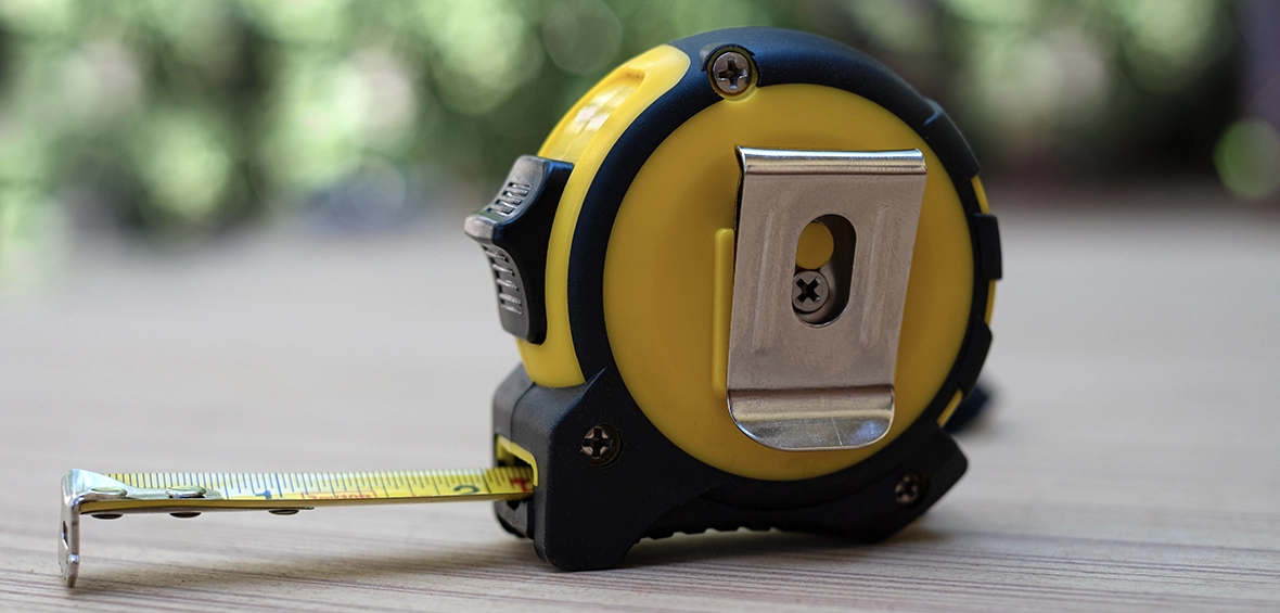 A yellow tape measure stands upright and is slightly extended with 2.25 inches of tape visible.