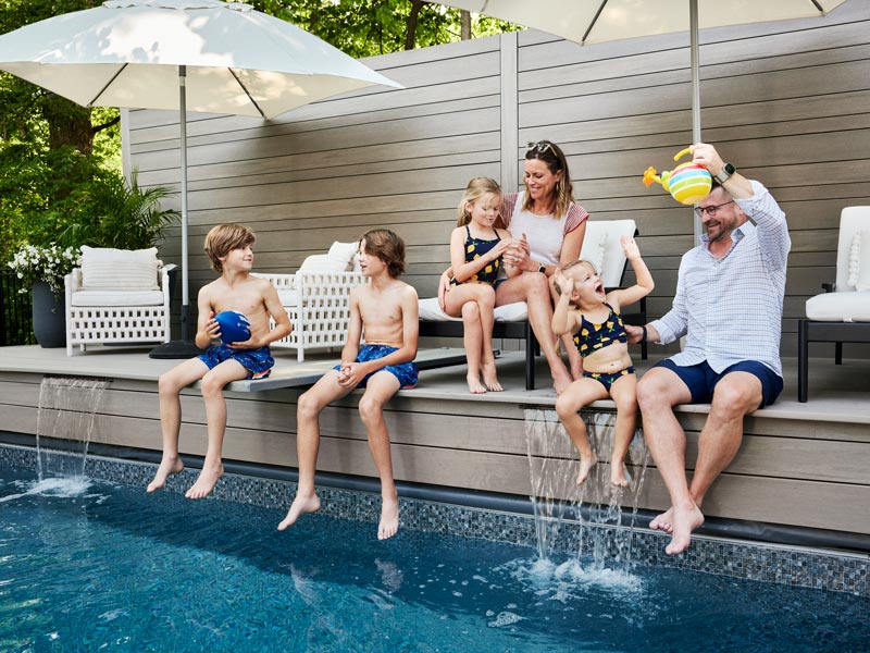 Elizabeth, Scott, and their four children chat at the edge of their in-ground pool