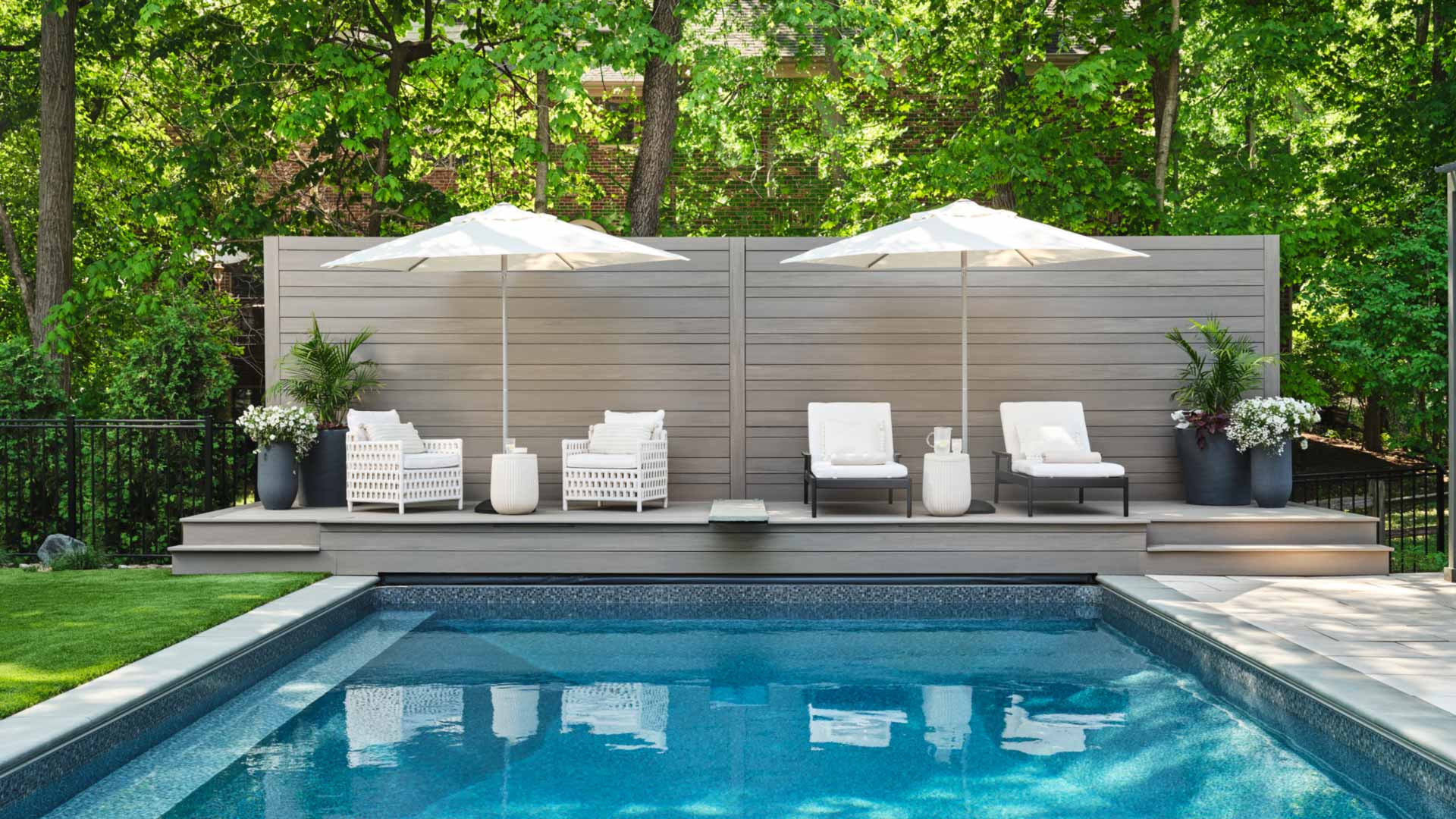 Shot of a gorgeous pool with a light gray deck taken from across the pool