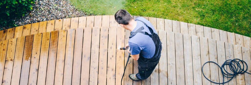 An overhead image shows a man pressure-washing a wood deck surface.