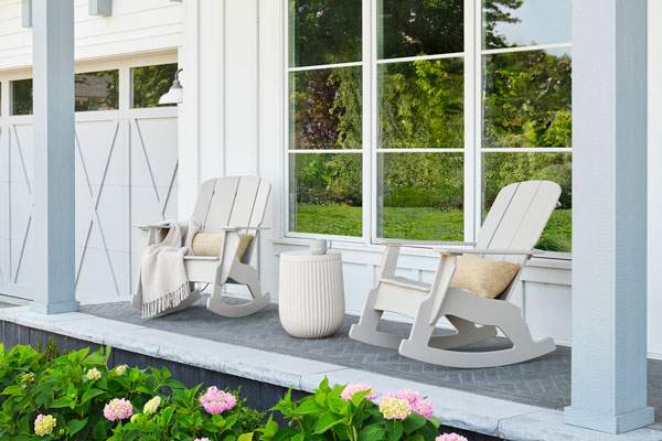 Two Lounge Rocker chairs sit on a porch, the lounge rockers are part of the Invite furniture collection