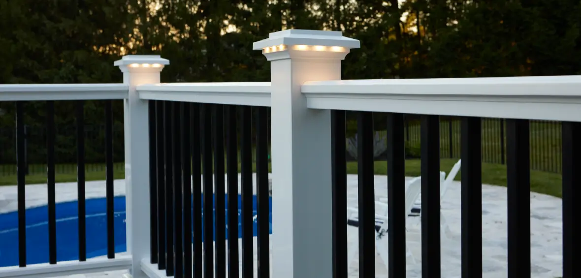 White railing and posts with lit post caps with contrasting black vertical balusters. 