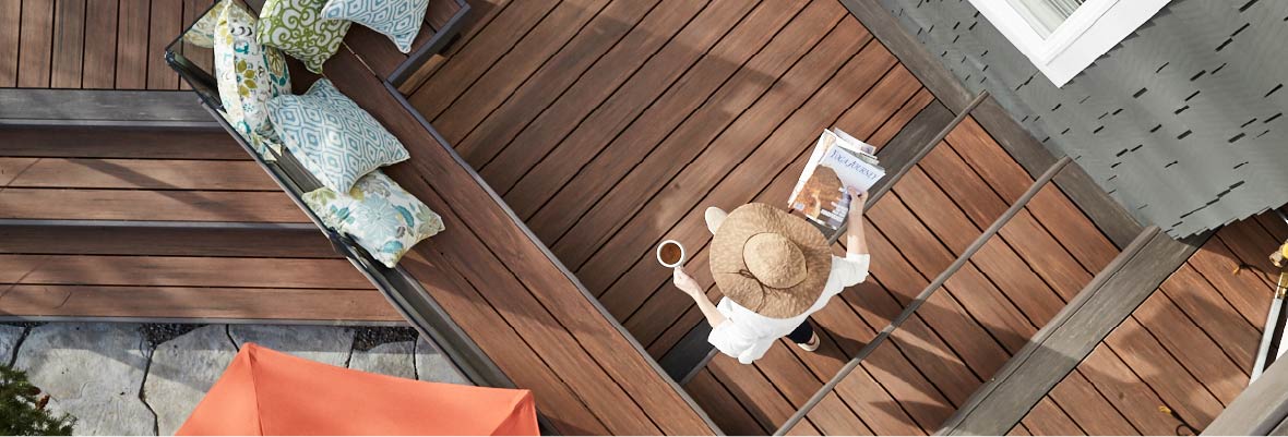 Overhead photo of a woman with coffee and a book walking across her deck.