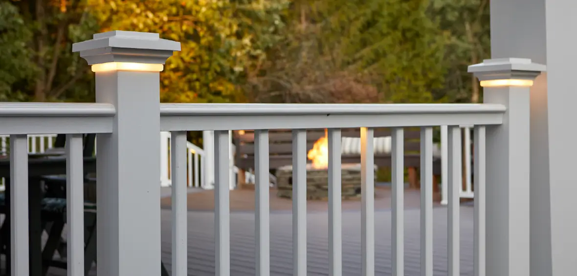 Two white post caps feature a light wrapped around the cap base above the railing for a gentle glow.