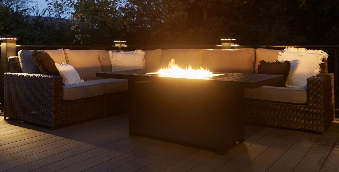 A composite deck in with a sectional sofa around a table-top firepit. 