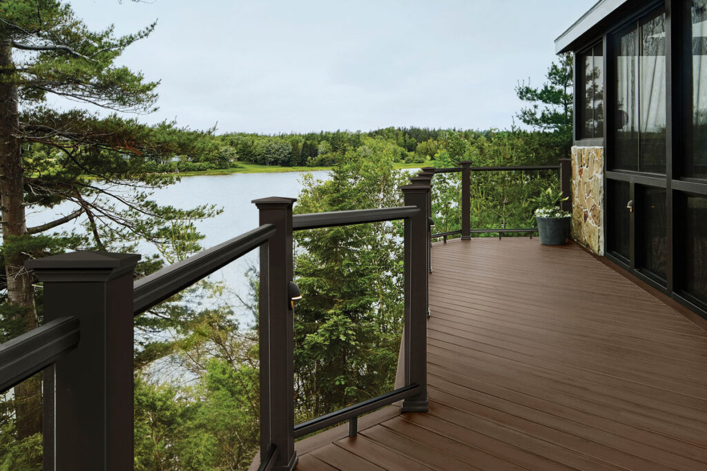 Deck made of richly hued brown deck boards attached to a lake house on the water