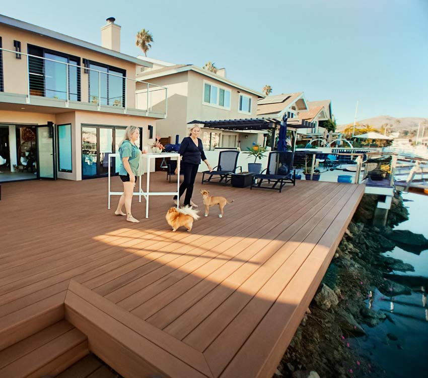 Paddi and a friend walk towards the edge of her deck on the water