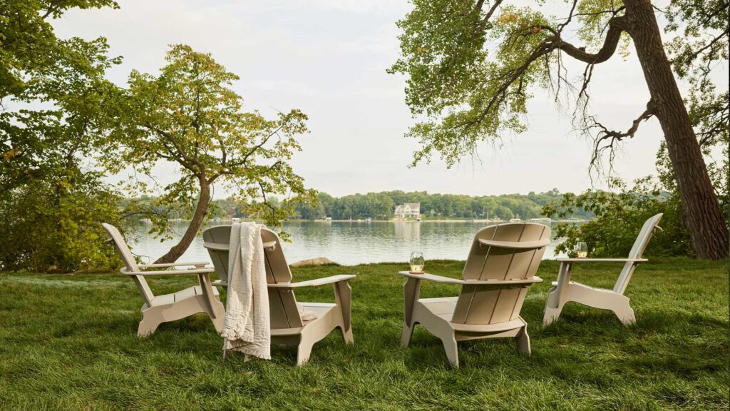 Four Adirondack chairs by a lake