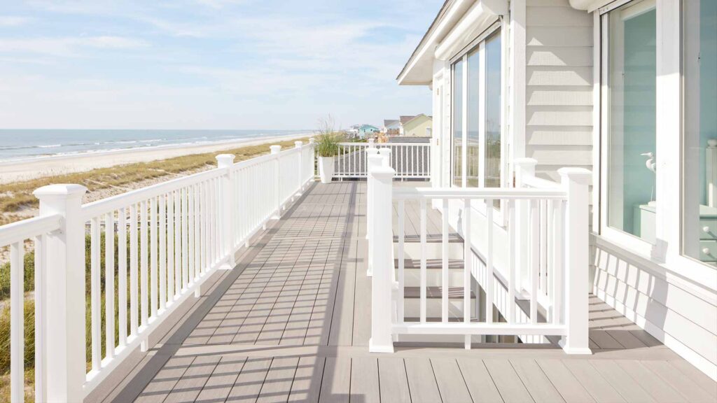 Beach house with gray deck with white railing on a bright day